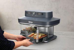 Ninja amplia la gamma CRISPi con la prima Friggitrice ad aria in vetro Ninja CRISPi DualZone a 2 contenitori in Italia 9 JPG A DD102UKBL1 InUse OnCounter Angled Left Woman RemovingGlassware Food 2